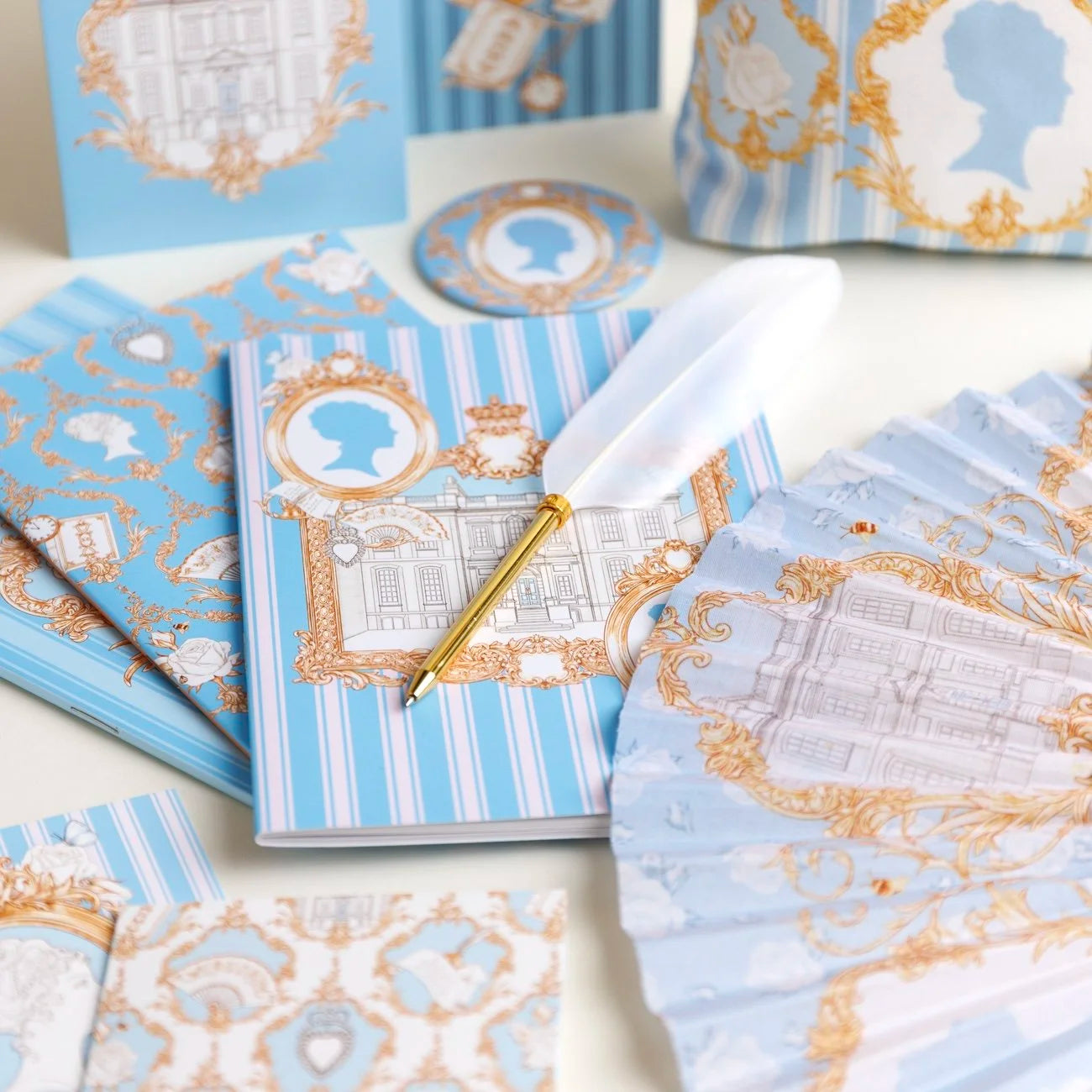 Photograph of decorative stationery items with heritage inspired blue, white and gold designs by Alexandra Rose Illustration for English Heritage on a white surface.