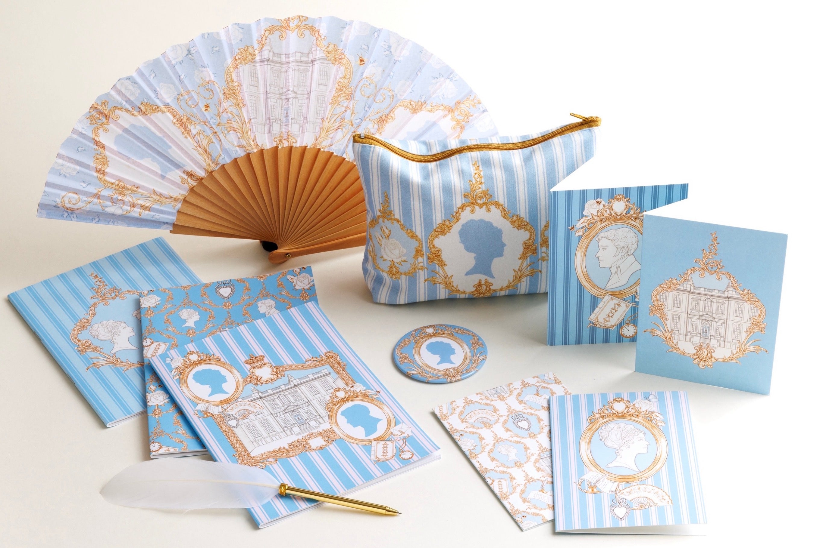 Product photography of a Regency Georgian inspired merchandise collection for Cultural Enterprise English Heritage. Illustrated items including a handheld fan, notebooks, cosmetic bag and pocket mirror with decorative designs on a white background.